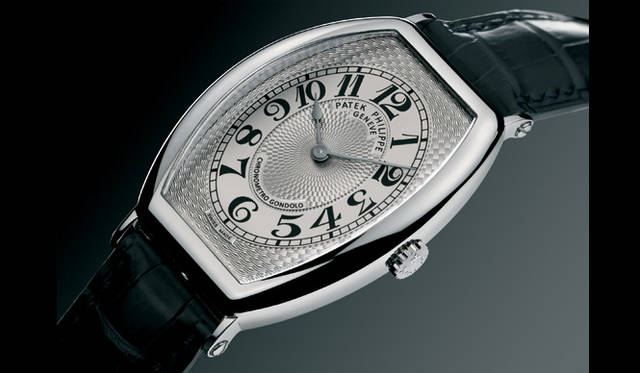 <strong>PATEK　PHILIPPE｜パテック フィリップ</strong>　ラグに向かって流れるようなトノー型フォルムを見せるパテック フィリップ／クロノメトロ・ゴンドーロ 5098。ロジウムメッキが施されたゴールド文字盤には、美麗なギョーシェ装飾が敷き詰められている。スペード型の時針＆分針にはブラックゴールドを採用。