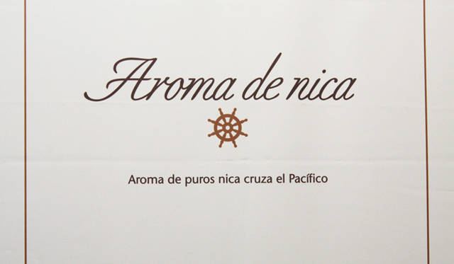 日本発、ニカラグア産のプレミアム・シガー「アロマ・デ・ニカ」のブランド・ロゴ。ロゴ・マークは船の「舵」を表しているが、これは葉巻が1492年コロンブスの第一回航海によってヨーロッパに持ち帰られたことに由来している