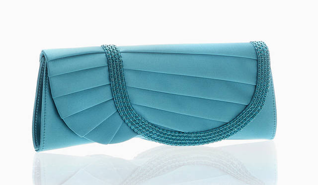 プリーツをたたんだうえにビーズが縫い取られたフラップは、背面も同じデザイン。サテン地がターコイズ色にやさしく光るクラッチ。バッグ 21万円（ジョルジオ アルマーニ／ジョルジオ アルマーニ ジャパン｜03-6274-7070）