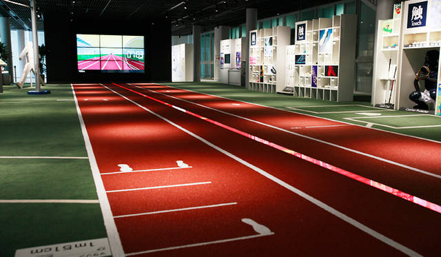 「アシックススポーツミュージアム」1階アスリートフィールド<br>陸上競技の種目の世界記録や野球のピッチングのスピードに合わせて、フィールドのセンターに光が走る床面に埋め込まれた20メートルのLED速度体感システム