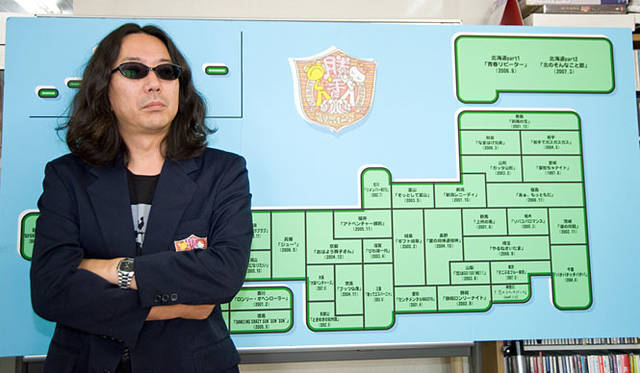 タモリ倶楽部で使われた『勝手に観光協会』全国マップの前にて、オフシャルのブレザーを着るみうら氏