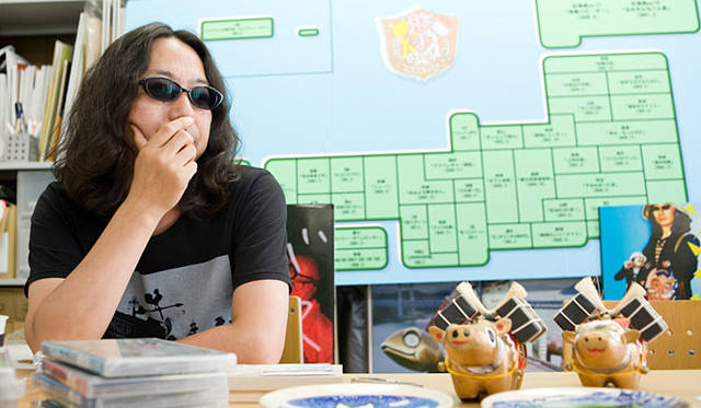 『勝手に観光協会』のおみやげを前にするみうら氏