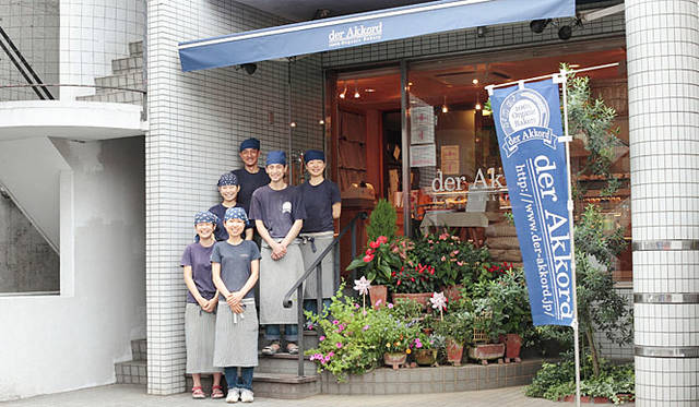 <b>アコルト（der Akkord）</b><br>社長の松尾氏とスタッフ。インディゴブルーの看板とのぼりが目印。店名はドイツ語で「和音」という意味。おいしいものが組み合わさって、もっとおいしくなるという願いが込められている