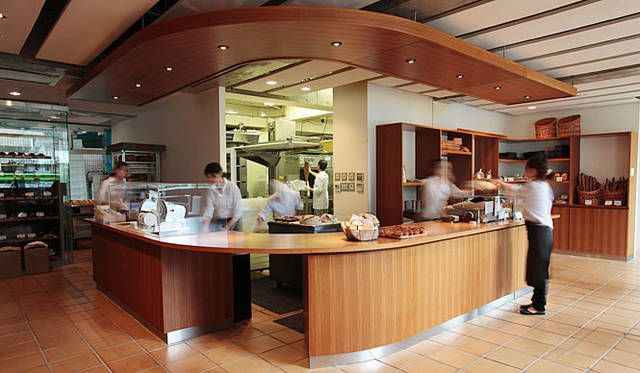 <b>Signifiant Signifié | シニフィアン・シニフィエ</b><br>店内中央には、どっしりとしたカウンターが。籠（かご）盛りにされたパンと、チーズのディスプレイウインドウに囲まれ、奥にはパン工房も垣間見える