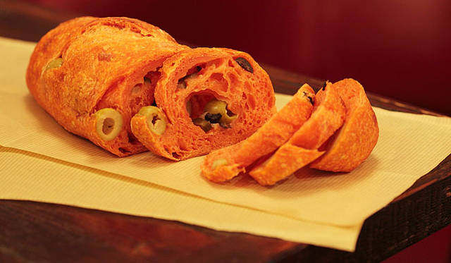 ネモ ベーカリー＆カフェ｜バゲット生地に、トマトピュレ、グリーン＆ブラックオリーブ、ピクルスが混ぜ込まれている「トマトフランス」は、バランスがよく、あとを引くおいしさ。もっちりとした食感でワインにもよく合う。焼き上がり予定時間 12:00　1本 250円