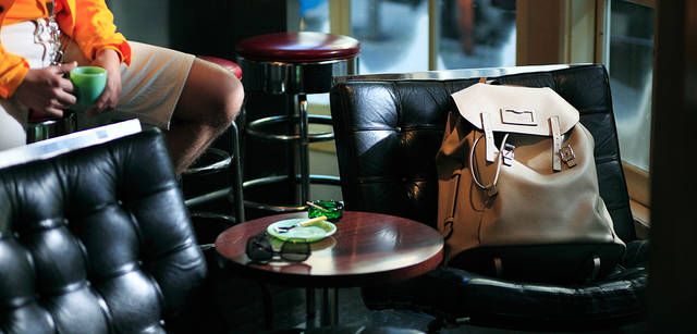 <strong>LOUIS VUITTON｜ルイ・ヴィトン</strong><br />すっかりこなれた雰囲気に仕上がった現場。背景にぼやけて見えるものの位置にまで、こだわりぬいている。モデル｜リュック「サック・ア・ド」55万1250円、ペンダント4万7250円（参考価格）、ジャケット20万1600円、ニット14万2800円、ショーツ8万2950円、テーブルに置いたサングラス5万1450円（すべてルイ・ヴィトン／ルイ・ヴィトン カスタマーサービスセンター　Tel. 03-3478-2100）