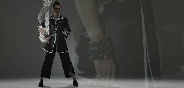 AS collection｜アズ コレクション｜天然石のジュエリーは気軽に取り入れられるアイテムのひとつ。ここではロングネックレスを斜めがけし、手首に幾重にも重ね着けし、全体のコーディネイトとしてボリュームとバランスをもたせた。(ジュエリー：すべてAS collection Tel. 03-5468-6835)、シャツ 2万5200円、パンツ 36万7500円（スーツ価格）、タイ 1万8900円、シューズとコートは参考商品（すべてトム ブラウン／ステディ スタディ　Tel. 03-5469-7110）