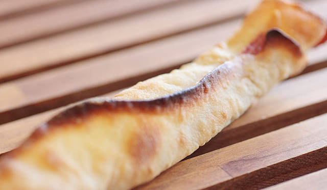 <b>Boulangerie Sudo｜ブーランジェリー スドウ</b>　イタリア産の生ハムを1枚とエダムチーズを、クリスピーな生地でくるっと巻いて焼いた「プロシュート」。黒コショウがアクセントになり、ワインとの相性も抜群。焼き上がり予定時間 9:00　1個350円