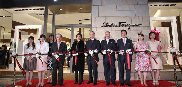 　オープニング当日の夕方、ショップ前で行われたテープカット。写真左からカーリング女子日本代表「チーム青森」の山浦麻葉選手、目黒萌絵選手、石崎琴美選手、森ビル代表取締役社長 森稔 氏、ヴィンチェンツォ・ペトローネ駐日イタリア大使ご夫妻、サルヴァトーレ フェラガモ イタリアCEOミケーレ・ノルサ氏、フェラガモ・ジャパン 代表取締役社長 那波史郎氏、本橋麻里選手、近江谷杏菜選手。