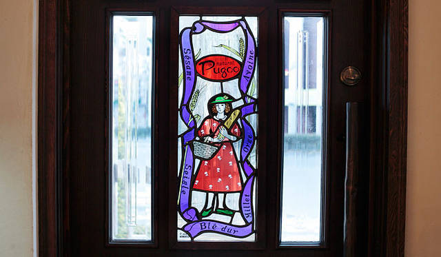 <b>Natural Puquu |天然酵母パン＆カフェ ナチュラル・プクゥー</b>　入口ドアには、ジブリ美術館のステンドグラスも手がけた山梨県在住のステンドグラス作家、八田高聡さん・ゆり子さんの作品が。夏は朝日が床に映ってとても美しいそうだ。