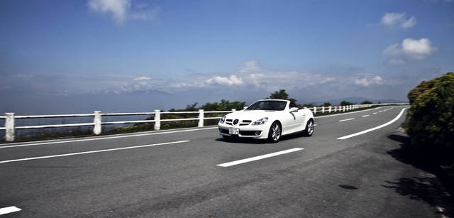 <b>Mercedes-Benz｜メルセデス・ベンツ SLK</b>　伊豆スカイラインは、夏にはとりわけ見事な光景だ。沿道の木が緑のトンネルのようになり、木漏れ日が太陽の光の美しさを強調する。そこを抜け、『arcana izu』へと走るのは、いいクルマだからこその楽しさ。