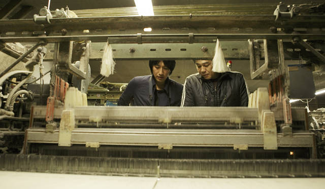 <b>MIHARAYASUHIRO｜三原康裕</b> カネタ織物の太田社長から貴重な旧式のシャトルドビー織機の説明を受ける三原さん