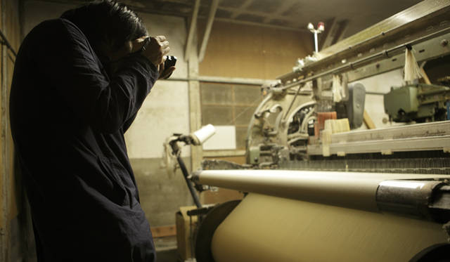 <b>MIHARAYASUHIRO｜三原康裕</b> 希少なシャトル織機を前に、三原さんは自身で持参したカメラのシャッターを切る