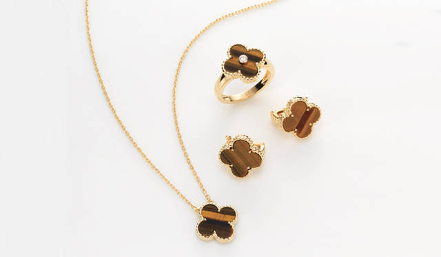 <strong>ヴァン クリーフ＆アーペル</strong>　「ヴィンテージ アルハンブラ」　右上から／リング[YG×タイガーアイ×ダイヤモンド] 、イヤクリップ[YG×タイガーアイ] 、ペンダント [YG×タイガーアイ] （すべてヴァン クリーフ＆アーペル／ヴァン クリーフ ＆ アーペル ル デスク）