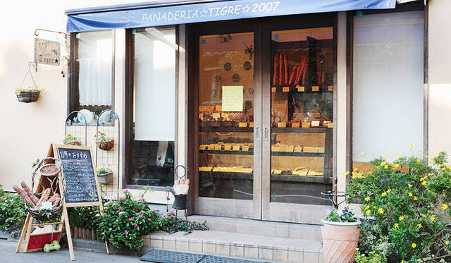 <strong>PANADERIA TIGRE｜パナデリア ティグレ</strong>　やわらかい黄色の外壁が印象的な外観。大きな引き戸を開けると、焼きたてパンの香ばしい香りが広がる。