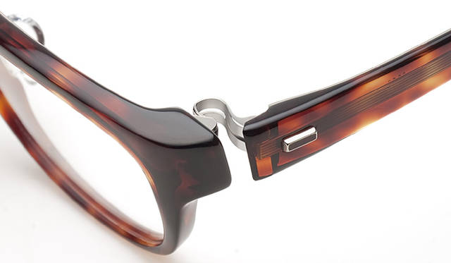<strong>999.9｜フォーナインズ</strong>　NP-90 col.502。装飾：テンプルに装飾を配し、さらなる質感の向上を目指している。チタンの土台のなかに、プラスチック生地と同系のカラーが映える。曲智からダブル逆Rヒンジ、装飾、テンプルというフロントからサイドへの流れが、品質感を引き立てる。