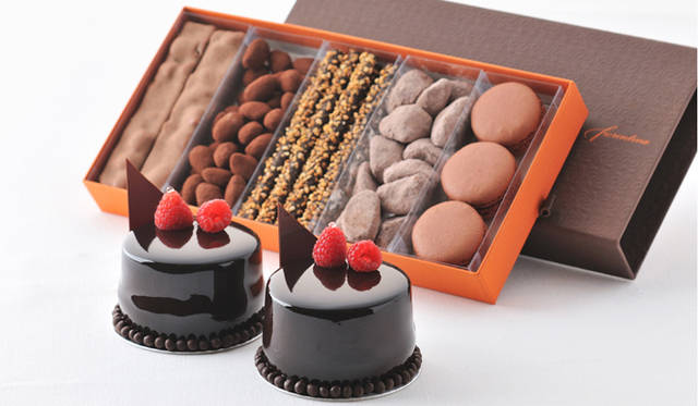 <strong>GRAND HYATT TOKYO｜グランド ハイアット 東京</strong><br />手前｜スペシャルチョコレートケーキ「ショック フランボ」　1000円　<br />後方｜バレンタインデイスペシャル　4000円（5種詰め合わせ）　写真左より、マシュマロ・ナッツ入り「ランゴショコラ」、アーモンドチョコレート「アマンディーヌ」、香ばしいアーモンドをアクセントにしたほぞ長いダークチョコレート「グリッシーニチョコレート」、優しい味わいのチョコレートクッキー「ショコラ ブールドネージュ」、そして「チョコレートマラロン」を詰め合わせたギフトセット