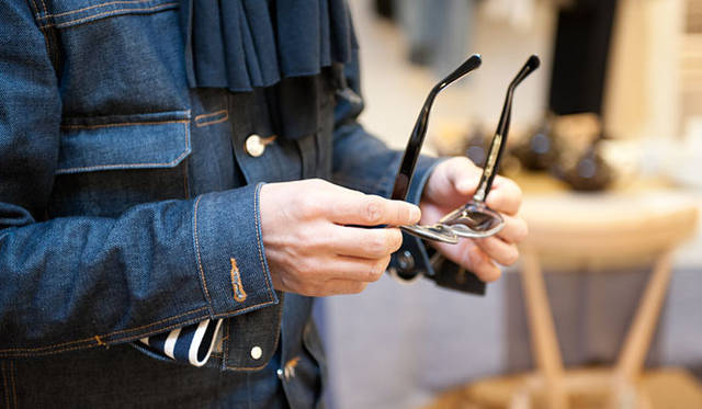 <strong>MARGARET HOWELL｜マーガレット・ハウエル</strong>　オリバー ゴールドスミスのモデルを手に取る。