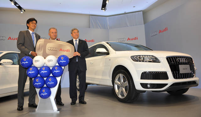 <strong>Audi｜アウディ</strong>　アウディ ジャパン 社長 大喜多 寛氏（左）、サッカー日本代表監督 アルベルト・ザッケローニ氏（中）、日本サッカー協会副会長　大仁邦彌氏（右）。そしてラグジュアリーSUVの「Q7」だ。