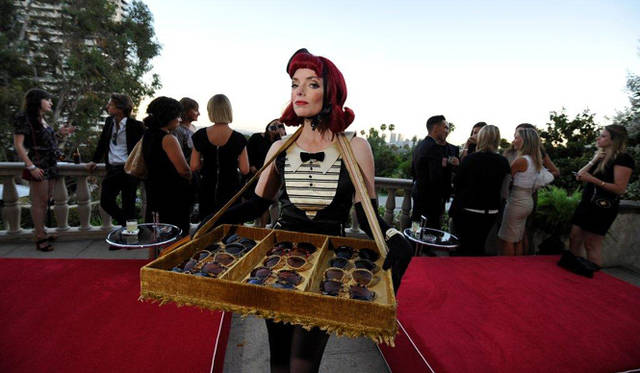 <strong>MIU MIU｜ミュウミュウ</strong>　ショートフィルム第2弾『MUTA』ロサンゼルスにてプレミア開催<br />イベントにはシガレットガールが登場し、ショートフィルムにて主人公が着用したミュウミュウの“ノワール”サングラスコレクションをゲストに配った。