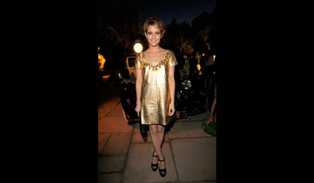 <strong>MIU MIU｜ミュウミュウ</strong>　ショートフィルム第2弾『MUTA』ロサンゼルスにてプレミア開催<br />エマ･ロバーツはこの日、襟もとにネックレスのようなビーズのトリムがほどこされた、ゴールドレザーのキャップスリーブドレスをセレクト。ドレスはもちろんミュウミュウのものだ。