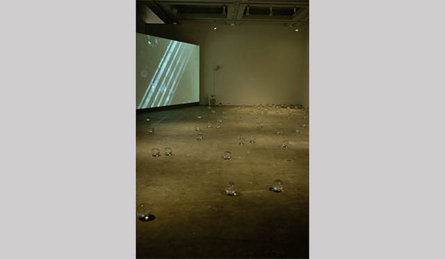 <strong>ヨコハマトリエンナーレ2011</strong>　ライアン・ガンダー  「何かを描こうとしていたまさにその時に私のテーブルからすべり床に落ちた一枚の紙」（手前）、リヴァーネ・ノイエンシュワンダー氏 「テナント」（奥・映像）