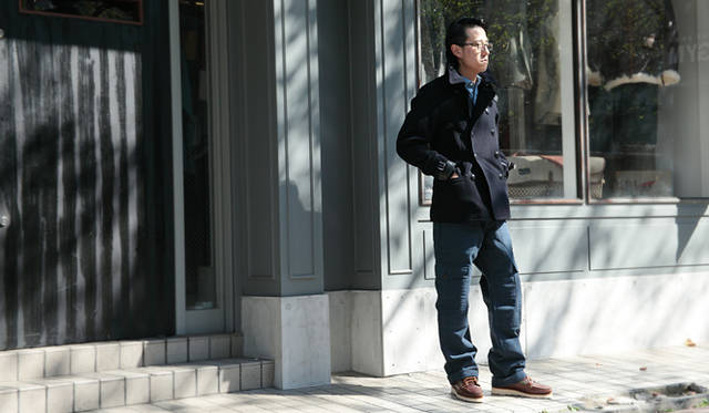 <strong>Nigel Cabourn｜ナイジェル・ケーボン　糸から開発した渾身のシャツ「BRITISH OFFICERS SHIRT」先行販売スタート！</strong><br />『THE ARMY GYM』サブショップマネージャー 高木裕一さん<br />ミリタリーピーコート　7万9800、ブリティッシュ オフィサー シャツ　1万9950円、ファティーグパンツ 　2万5200円（すべてナイジェル・ケーボン）、ブーツ チェック　8万2950円（ユケテン×ナイジェル・ケーボン）　すべてTHE ARMY GYM　Tel. 03-3770-2186