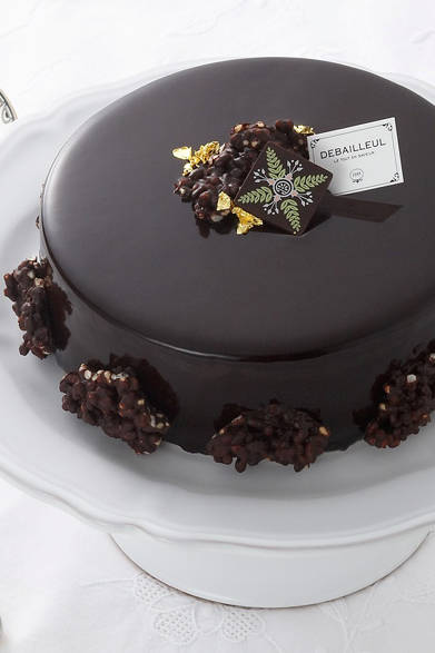 <strong>DEBAILLEUL｜ドゥバイヨル</strong><br />L`INOUBLIABLE～忘れがたきもの～<br />香り高いバニラ ビーンズをふんだんに使った、口当たりのなめらかなクレームブリュレを、濃厚なチョコレートムースで囲み、ベースには香ばしさと食感が楽しいクリスピーライスビスケットでアクセント。艶やかなダークグラサージュで全体を美しくコーティングし、仕上げにモミの葉をモチーフに描かれたオリジナルデザインのチョコレートと金箔、クリスピーライスショコラを飾り、洗練されたスタイルに。<br /><br />価格｜5250円（15cm） ※予約販売（数量限定）<br />販売店舗｜丸の内OAZO、丸ビル、大丸心斎橋店、岩田屋本店、ほか有名百貨店