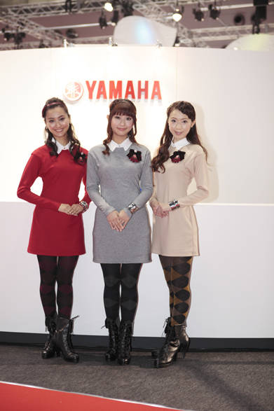 　色ちがいの襟つきニットワンピース×アーガイルのタイツ、胸もとのエンブレムブローチをアクセントに、“ブリティッシュ”“グッドガール”といった今季のトレンドキーワードをみごと押さえたヤマハのオリジナル衣装で旬なコーディネイトをみせたのはヤマハの3人娘。カラーを統一することで大人っぽく、落ち着いた雰囲気にまとめられていますね。アイドルみたいな清楚な雰囲気に癒されちゃいますね！