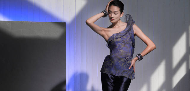 <strong>GIORGIO ARMANI｜ジョルジオ アルマーニ</strong>　植物や動物が描かれたトランスペアレントな生地を贅たくに使用したトップスを、コーディネイトのメインに。ワンショルダーに波打つようなディテールがポイント。トップス  参考商品 、パンツ 7万6650円 、ブレスレット  参考商品 （すべてジョルジオ アルマーニ）