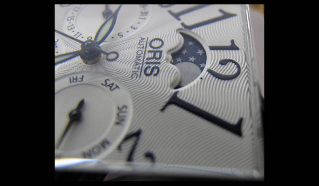 <strong>ORIS｜オリス</strong>　ギョーシェ彫りの文字盤。月に顔はない。ムーンフェイズ窓の点（月齢でいうと21日あたり）はゴミではなく「12」の一部。