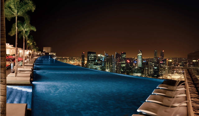 <strong>Marina Bay Sands Singapore｜マリーナ・ベイ・サンズ</strong>　プールは23時まで利用できるので、“あの”コマーシャルを再現することも可能！　クラブ・ラウンジ「クデタ」から聞こえてくる音楽や人びとのざわめきが、開放的なナイトスイムに華やぎを添える