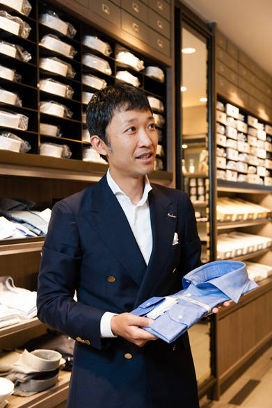 <strong>阪急MEN’S TOKYO｜6月 “ハイセンスに楽しむクールビズ”</strong>　「HITOYOSHI」のシャツを手に話す豊川氏が着用しているのはカッタウェイのシャツ