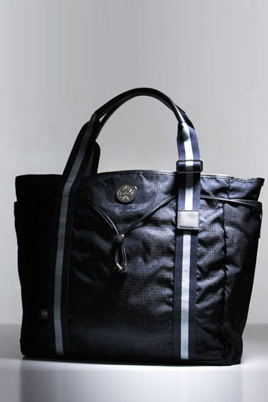 モノグラム調のナイロン生地を使ったトートは、ユニバーサル ランゲージの別注モデル。ジャケットスタイルにマッチするほどよいサイズを採用。小物類を入れるのに重宝するファスナー付きポケットが設けられ、ビジネスシーンを意識した作りとなっている。上品なネイビーの色合いもスーツに映えるはずだ。H36.5×W37×D15cm。<br /><br />2万4900円（オロビアンコ）<br /><br />ユニバーサルランゲージ 渋谷店<br />Tel. 03-3406-1515<br />http://www.orobianco.com/