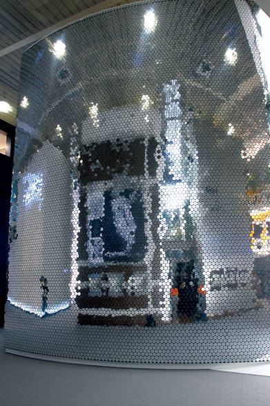 <strong>SWAROVSKI│スワロフスキー</strong> デザイナー吉岡徳仁氏が今回着想を得たという、2009年のバーゼルワールドのスワロフスキーブース。無数の小さなミラーにより、風に揺れ動くようなきらめきをもたらしたファサードは、湖の表面に美しい波紋を広げるような情緒豊かな輝きを生み出している。