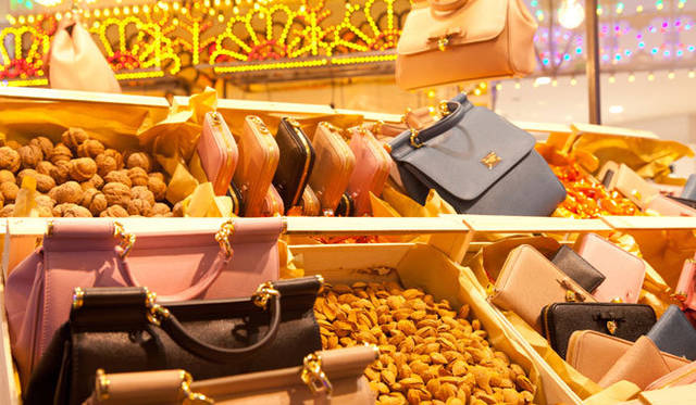 <strong>DOLCE&GABBANA｜ドルチェ＆ガッバーナ</strong>　ピンク、ベージュ、ブルーなどの淡い色合いが美しい「シシリー」の、バッグやパースが、アーモンドやチョコレートとともに並べられている