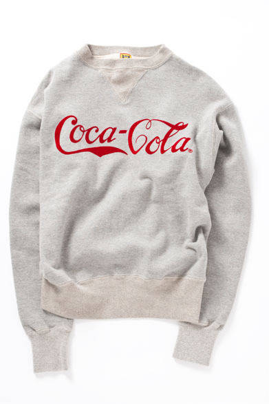 <strong>BEAMS｜ビームス</strong>　「COCA-COLA×HUMAN MADE×BEAMS」コレクション　コットンのスウェットシャツが出はじめた戦前のディテールで作成。現在では希少価値の高い、吊り編み機による生地を用い、縫製はアメリカンインチサイズのミシンで縫っているため、運針や縫い巾もインチサイズに仕上がっている。単糸で編まれた生地は吊り編みの空気をふくんだ風合いとともに洗いこむほど斜行し、プリントにも独特の歪みが生まれてくる。当時のハンドメイド感のある吹き付けによるフロッキープリントを表現するため、シンプルかつクラシックな1910年代の「Coca-Cola」ロゴをチョイス。スウェットシャツ1万8690円