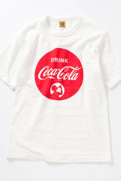 <strong>BEAMS｜ビームス</strong>　「COCA-COLA×HUMAN MADE×BEAMS」コレクション　1940年代のTシャツを意識したムラ糸使用のボディが特徴の「HUMAN MADE」定番Tシャツに、1930～40年代のクラシックかつポップなデザインのロゴを染み込みのプリントで表現。独特の横段の見えるような生地の風合いは、コンピュータ制御のスラブ糸ではなく、自然なムラ糸を作ることにより生まれるもので、このボディにビンテージの柄をプリントすることで生まれるムラがさらに映える。ネックラインは伸縮することで、ある程度までこなれたヨレ感が生まれ、伸び過ぎ防止のためフライスに段差を付けて縫製している。Tシャツ8190円