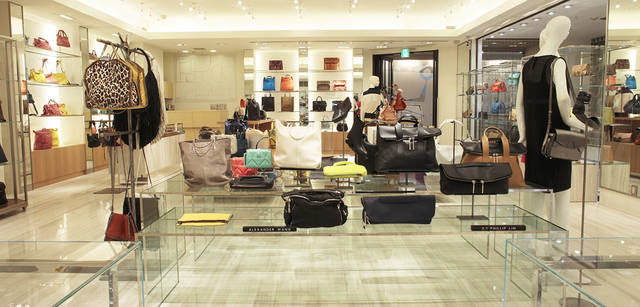 <strong>BARNEYS NEW YORK｜バーニーズ　ニューヨーク</strong>　「バーニーズ　ニューヨーク新宿店」ウィメンズフロアリニューアル　＜1階＞　トラバーチンとネスト（入れ子）テーブルのガラス、おなじくテーブルの木が共存して、大人の女性が心地良く感じる空間を創出