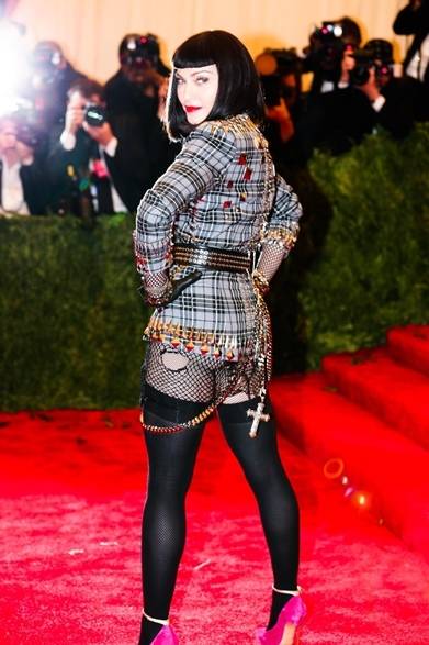 <strong>Madonna｜マドンナ</strong><br /><br />ジバンシィ バイ リカルド ティッシを着こなすファッションアイコンのマドンナに注目。スタッズ付きのチェックジャケット一枚に、ネットタイツだけ。ヒップの露出が超大胆！　ド派手なパンクルックはさすがの貫録。<br /><br />Courtesy of The Metropolitan Museum of Art/BFAnyc.com