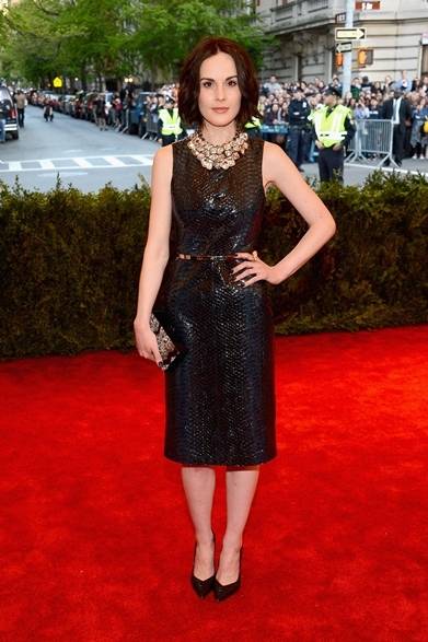 <strong>Michelle Dockery｜ミシェル・ドッカリー</strong><br /><br />ミニマルな黒のシンプルドレスで現れた女優のミシェル・ドッカリー。クロコのエンボス加工がほどこされたレザーで繊細なビターテイストを仕上げた。胸元のビジューネックレスとクラッチがゴージャスなパーティースタイルを完成させる。