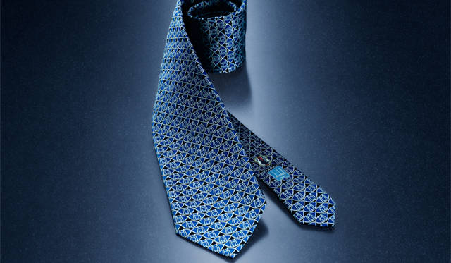 <strong>dunhill｜ダンヒル</strong>　これまで日本代表の試合の舞台となってきた、埼玉スタジアムを真上から見た図をモチーフにした、幾何学模様が織り込まれたネクタイ