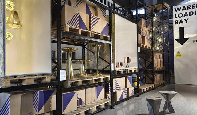 <strong>青木昭夫がリポートする「2013年サローネビューイング」</strong>　「MOST」Tom Dixon（トム・ディクソン）の展示。展示手法は工場や倉庫を想起させる無骨な見せ方。スチールラック、ダンボール、パレットで構成され、ところどころに既存のプロダクトや新作を発表 