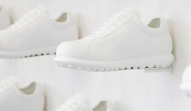 壁面を覆うのはカンペールの定番商品「Pelotas」を白い樹脂で成型したもの。天井の高い店舗では、店内上部に商品を陳列しにくい、かといってイメージビジュアルの掲示などでは、商品とビジュアルとが分離されてしまう。という課題を解決した