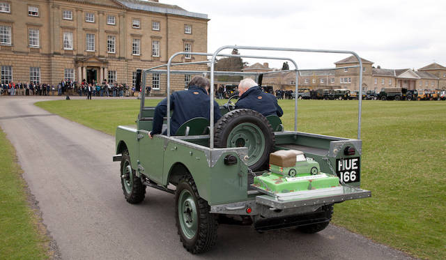 ランドローバー シリーズ1の第1号プリプロダクションモデル「HUE 166」をモデルにしたバースデーケーキを、その「HUE 166」で、ジャガーランドローバーのCEO ラルフ・スペス博士とランドローバー勤続最長記録のロジャー・クラットホーン（Roger Crathorne）氏がとどける