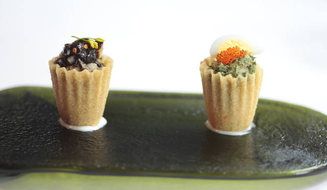 食べられる器「パイティー」のなかに、エビとラクサの葉のペースト和え（右）、スパイスを効かせたのりの佃煮を詰めた前菜メニュー。緑の皿は店で出たワインボトルをリサイクルしたもの