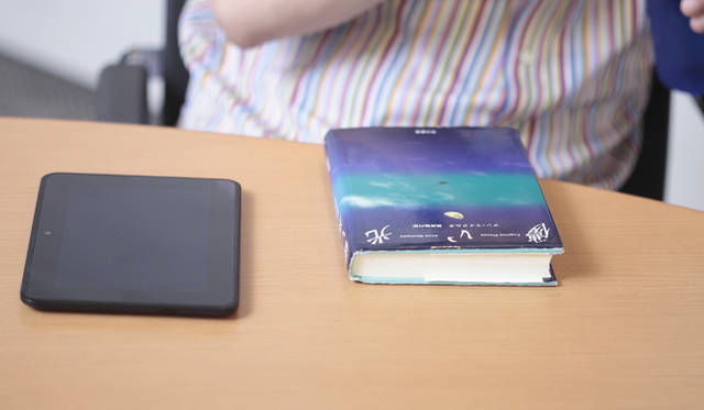 左が「kindle」。右が今、旅行する時には必ず持って行くという小説『儚い光』（アン・マイクルズ著／早川書房）。大学3年生の時に出会って以来、10冊以上も買い直しているという。現在早川書房での取り扱いはなく、書店、またはamazonや楽天ブックスなどのインターネットでわずかに在庫がある状況