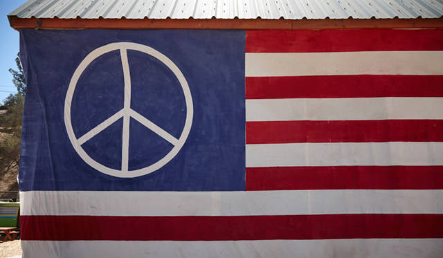 ピースマーク付きの巨大な星条旗がトパンガ・キャニオンの青空に溶け込む……