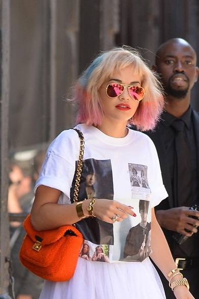 RitaOra <strong>Rita Ora|リタ・オラ</strong><br /><br />ニューヨークの街角でキャッチしたリタ・オラ。プリントTシャツと白いスカートのシンプルなカジュアルスタイルに、サングラスとバッグ、そしてユニークなヘアを鮮やかなアクセントを加える。