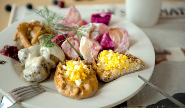 ミルク粥をライ麦の生地で包んだパイに卵とバターでつくる「ムナボイ」を乗せて食べるという「カルヤランピーラッカ」（写真手前）。クリスマスシーズンに欠かせないというサラダ「ロッソリ」やキノコのソテー、ミートボールを添えている